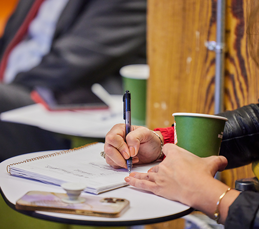 a focused image of a person writing with a pen on a notebook