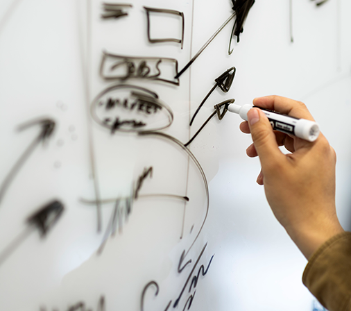 focused image of a hand drawing arrows on a white board