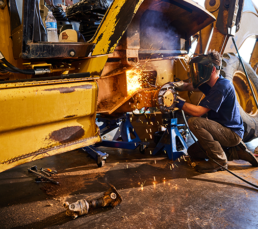 a man using a tool on a piece of equipment with sparks coming from tool