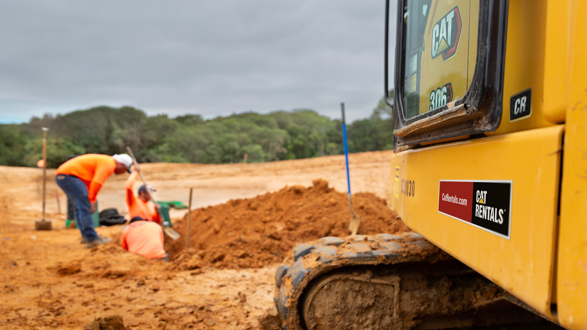 Cat Rentals excavator and workers at a construction site.