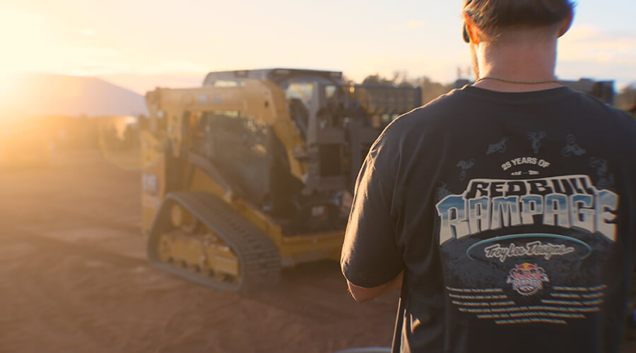 Person standing near Cat compact equipment at a Red Bull Rampage event.